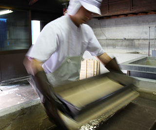 出来たての蒟蒻を灰汁水槽に移す